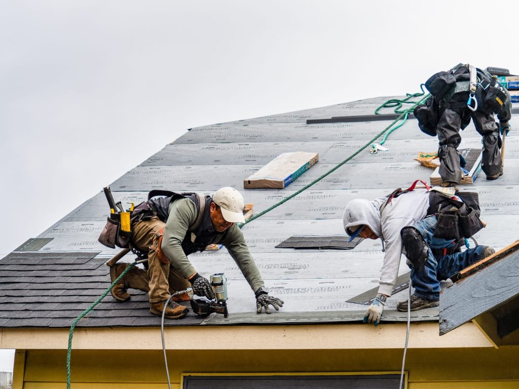 Everett WA. USA - 03-23-2021: Crew Installing New Shingles on Roof on a Rainy Day